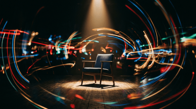 Empty cushioned chair under spotlight on wooden floor with colorful light trails swirling around